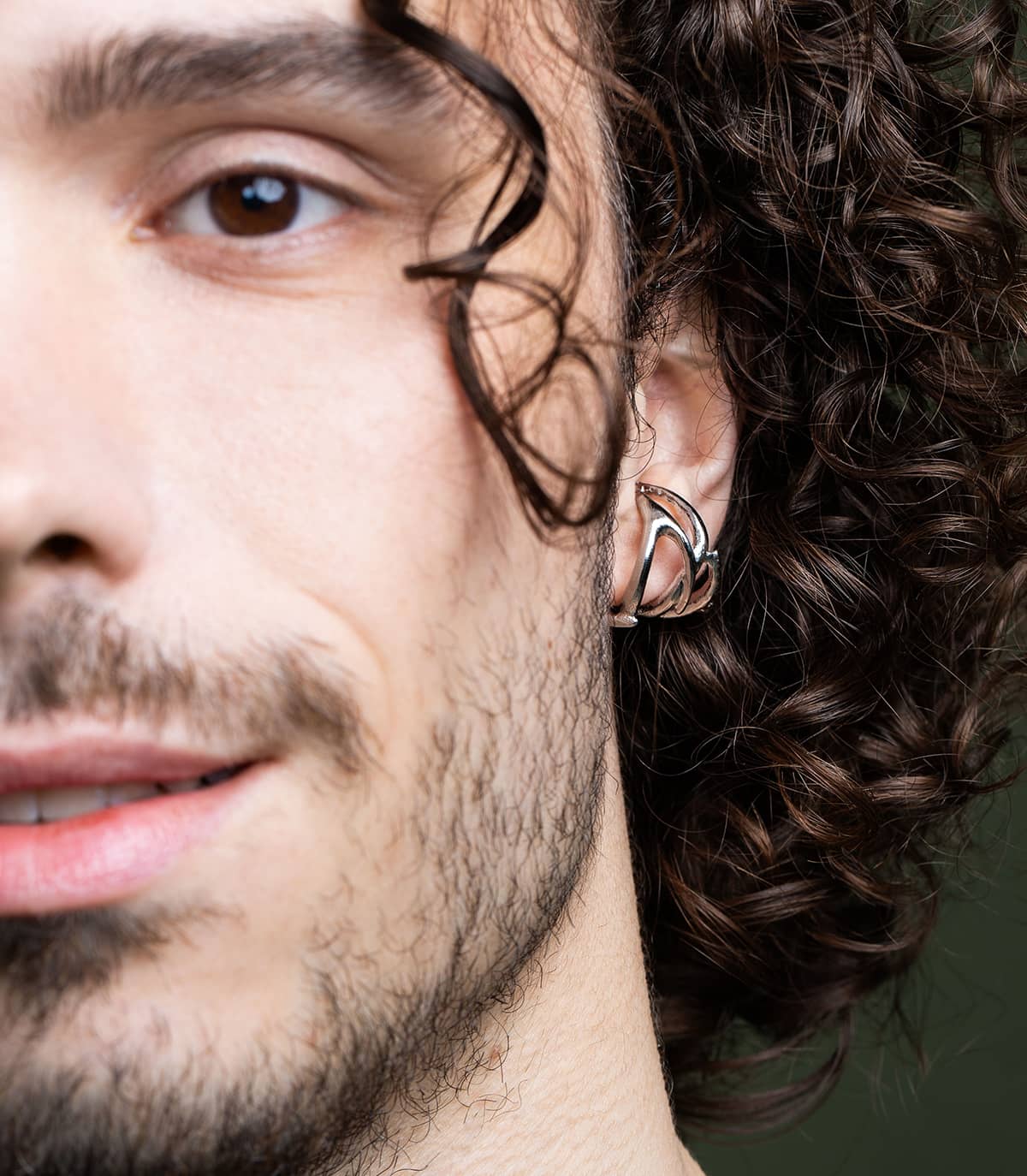 Moitié de visage d'un homme qui porte un anneau d'oreille argenté en forme de branches.