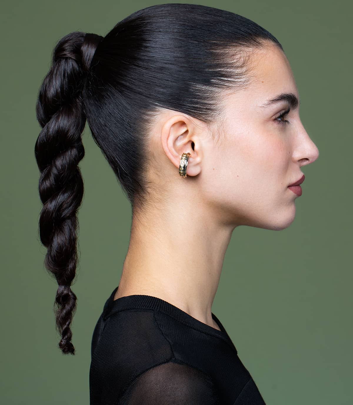 Une mannequin avec une queue de cheval porte l'anneau d'oreille strass doré